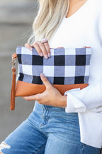 Woman holding buffalo plaid clutch bag with leather wristlet, styled casually with denim.