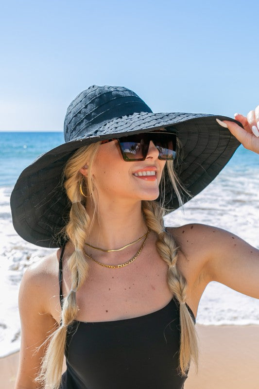 Woman wearing white wide-brim sunhat with bow on beach
