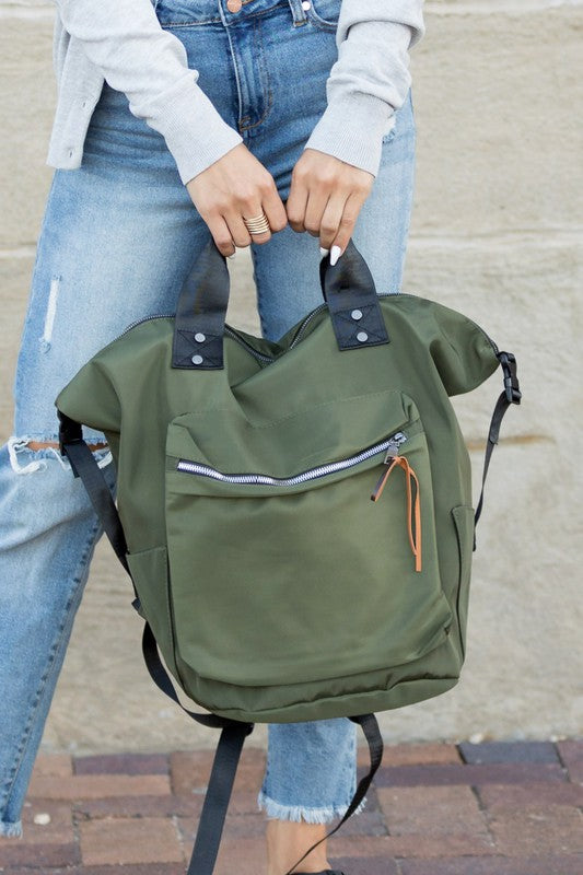 A woman is holding a backpack tote. She is wearing a casual outfit.