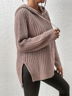 This is a picture of a woman posing in a hooded sweater. The sweater is a high-low design with a slit on the side. It has a drawstring hood and long sleeves.