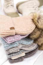 Assortment of cozy marled knit beanies with faux fur pom-poms, available in multiple colors.