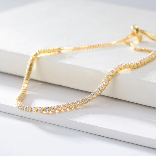 Gold Alicia bracelet with cubic zirconia on white surface
