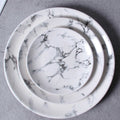 Overhead view of a white marble ceramic round plate set with elegant gray veining