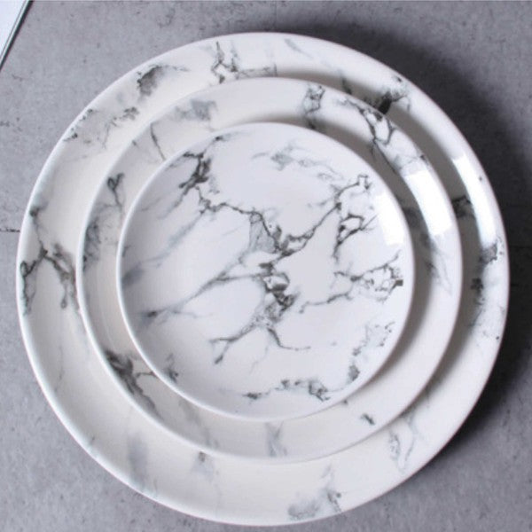 Overhead view of a white marble ceramic round plate set with elegant gray veining