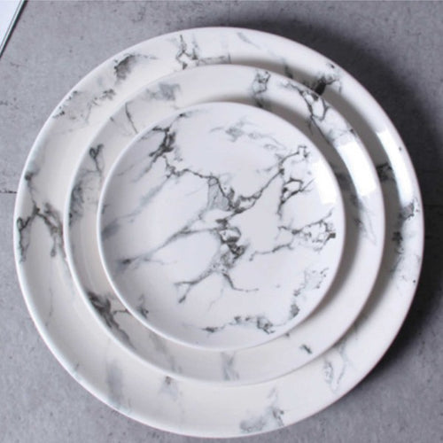 Overhead view of a white marble ceramic round plate set with elegant gray veining